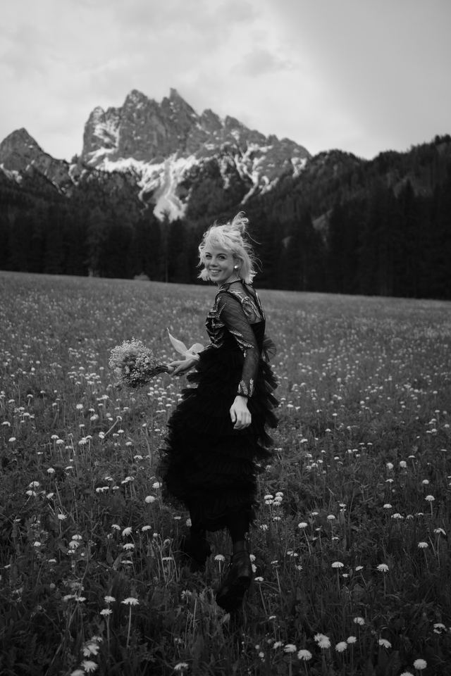 Woman running through alpine meadow with bouquet